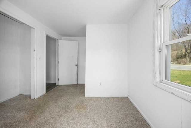 unfurnished bedroom with baseboards, multiple windows, and carpet flooring