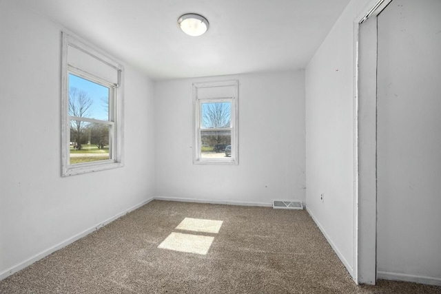 empty room featuring visible vents, baseboards, and carpet flooring