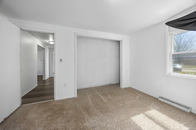 unfurnished bedroom with a closet, a baseboard heating unit, baseboards, and carpet