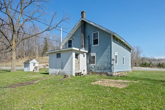 rear view of house with a yard, an outdoor structure, and a chimney