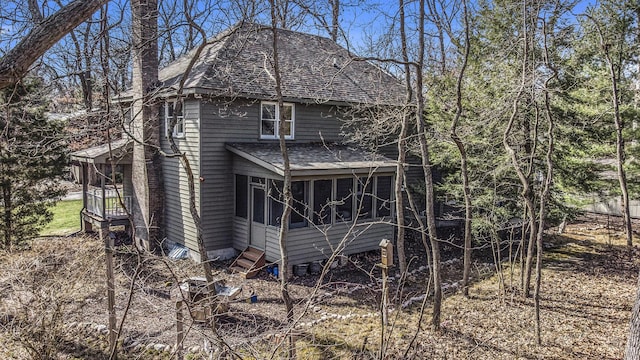 rear view of property with a sunroom and roof with shingles