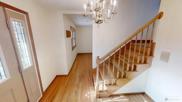 entrance foyer with a chandelier, stairs, baseboards, and wood finished floors