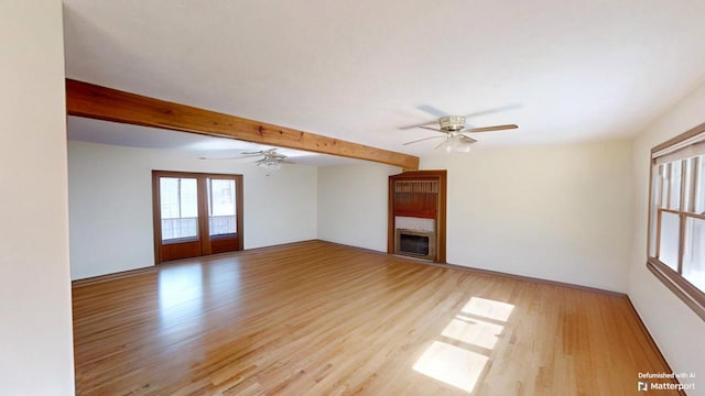 unfurnished living room featuring light wood-style flooring, ceiling fan, a fireplace, and beam ceiling
