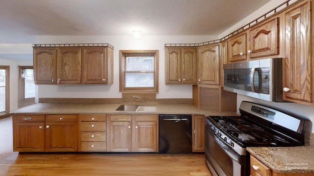 kitchen featuring stainless steel appliances, plenty of natural light, light wood-style floors, and a sink