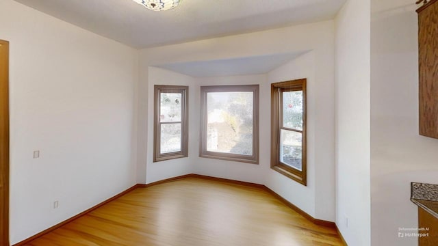 unfurnished room featuring baseboards and light wood finished floors