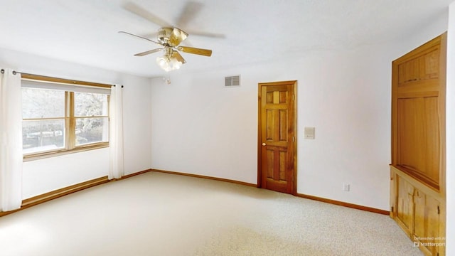 empty room with visible vents, light colored carpet, baseboards, and ceiling fan