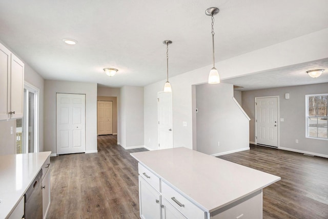kitchen featuring dark wood-style flooring, baseboards, a center island, light countertops, and white cabinets