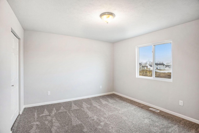 unfurnished room featuring a textured ceiling, carpet flooring, baseboards, and visible vents
