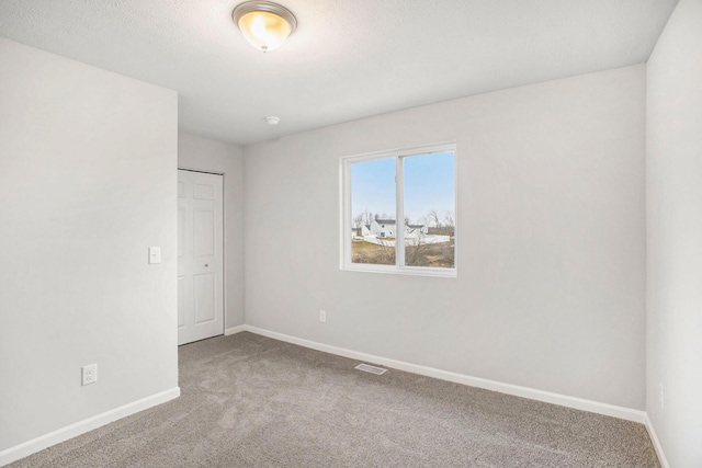 empty room with baseboards, visible vents, and carpet floors