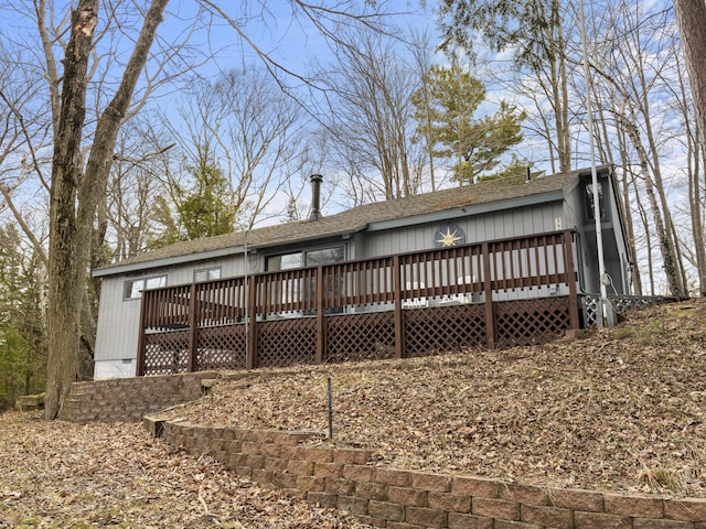 back of house featuring a deck and roof with shingles