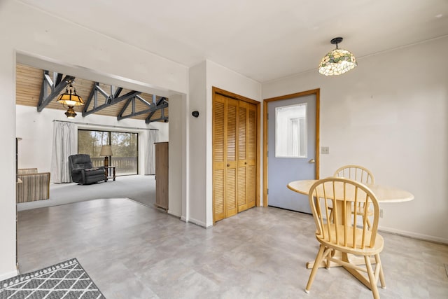 interior space with concrete flooring, baseboards, and lofted ceiling with beams