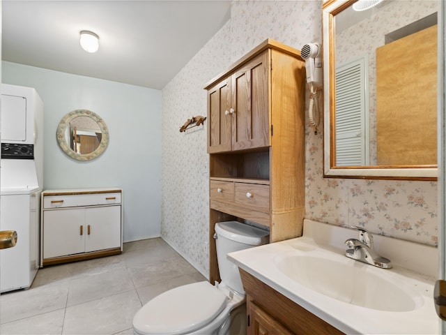 bathroom featuring tile patterned floors, stacked washer and dryer, wallpapered walls, and toilet