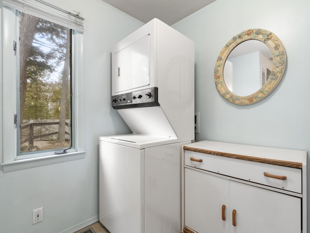 laundry room featuring stacked washer / dryer and cabinet space