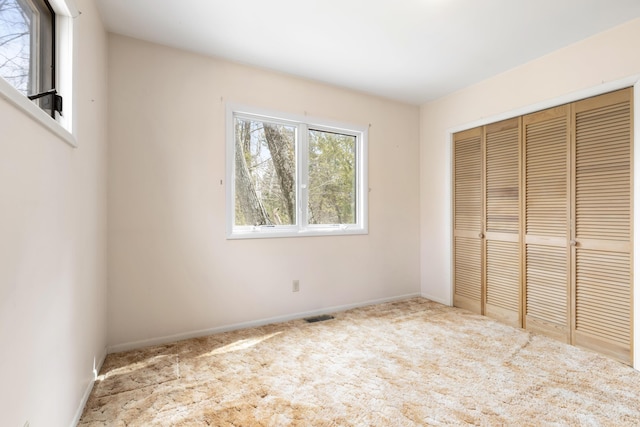 unfurnished bedroom with a closet, carpet flooring, baseboards, and visible vents