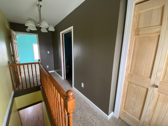 hallway with baseboards, an upstairs landing, and carpet