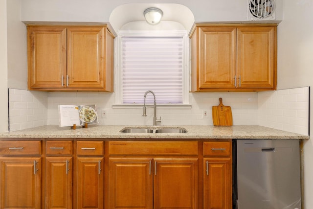 kitchen featuring stainless steel dishwasher, tasteful backsplash, light stone countertops, and a sink