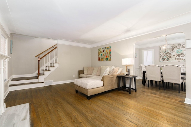 living area featuring visible vents, baseboards, wood finished floors, and stairs