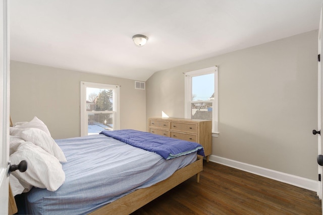 bedroom featuring dark wood-type flooring, visible vents, baseboards, and vaulted ceiling