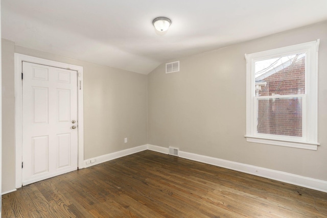 unfurnished room featuring visible vents, baseboards, lofted ceiling, and dark wood finished floors