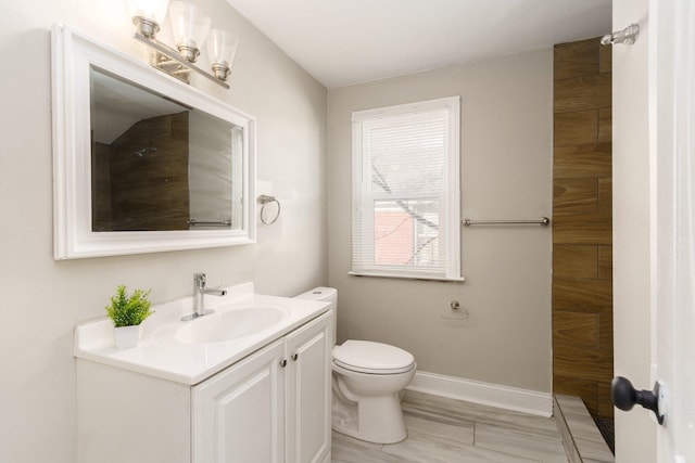 bathroom featuring toilet, vanity, and baseboards
