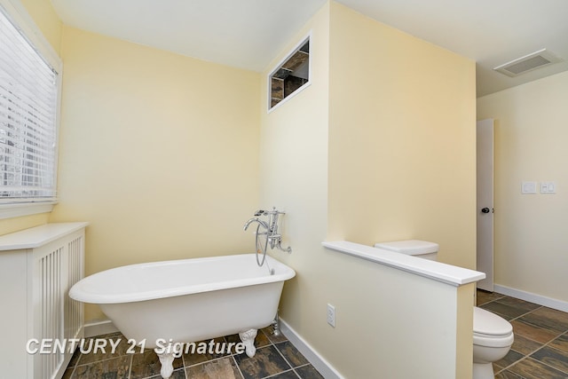 105 Parkwood Ct, Bay City, MI 48706 - full bath featuring visible vents, baseboards, a freestanding tub, toilet, and stone finish floor