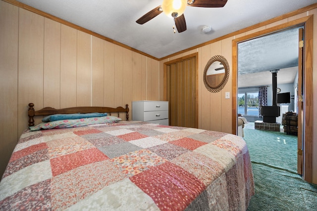 bedroom featuring ornamental molding, carpet floors, a wood stove, access to exterior, and ceiling fan