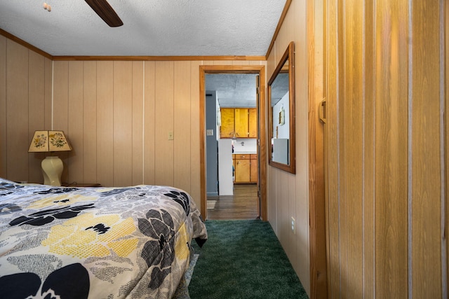 carpeted bedroom featuring a textured ceiling, wooden walls, and ceiling fan