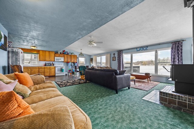 carpeted living room featuring a textured ceiling, ceiling fan, and a water view