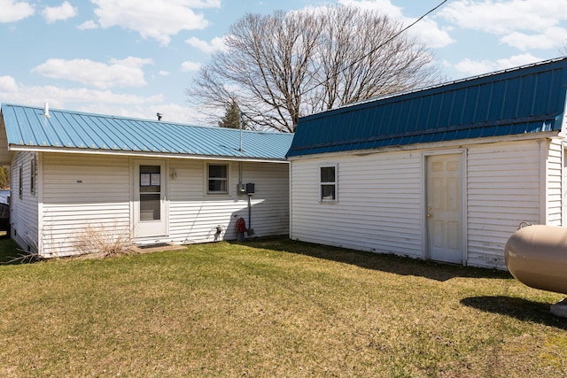 rear view of property featuring a yard and metal roof