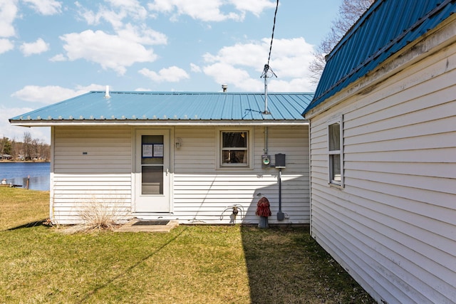 rear view of property featuring a yard, metal roof, and a water view