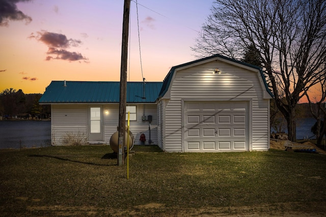 ranch-style home with a garage, metal roof, a gambrel roof, and a lawn