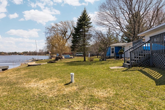 view of yard featuring a deck with water view and stairs