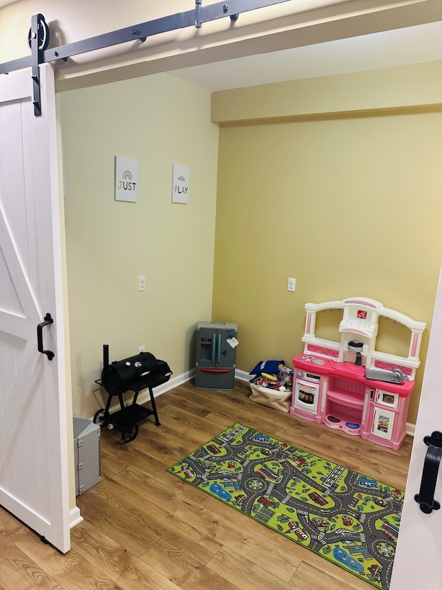 133 Bingham Dr, Brooklyn, MI 49230 - game room featuring a barn door, wood finished floors, and baseboards