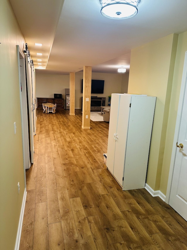 133 Bingham Dr, Brooklyn, MI 49230 - corridor featuring a barn door, wood finished floors, and baseboards