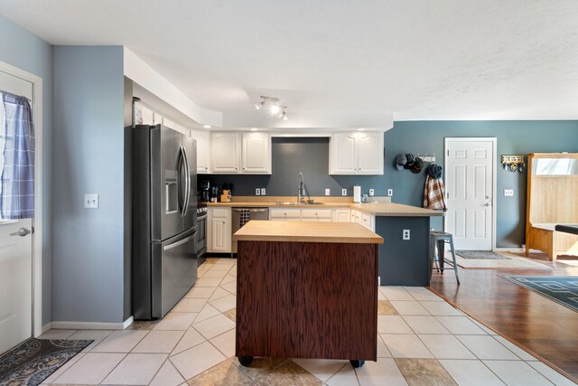 14204 Northmoor Dr, Cement City, MI 49233 - kitchen featuring a peninsula, a sink, light tile patterned floors, and appliances with stainless steel finishes