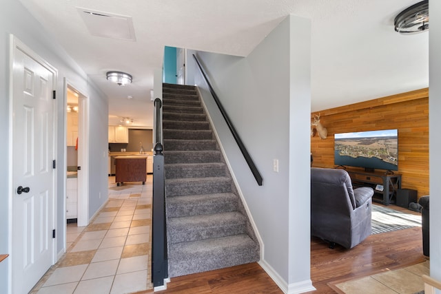 14204 Northmoor Dr, Cement City, MI 49233 - stairs with wooden walls, tile patterned floors, an accent wall, and baseboards