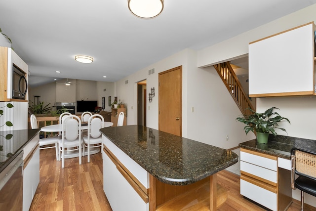 3755 Oak Dr, Ypsilanti, MI 48197 - kitchen with dark stone countertops, visible vents, light wood-type flooring, black microwave, and a kitchen island