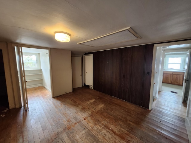 309 N Main St, Scottville, MI 49454 - unfurnished bedroom featuring hardwood / wood-style floors, attic access, multiple windows, and visible vents