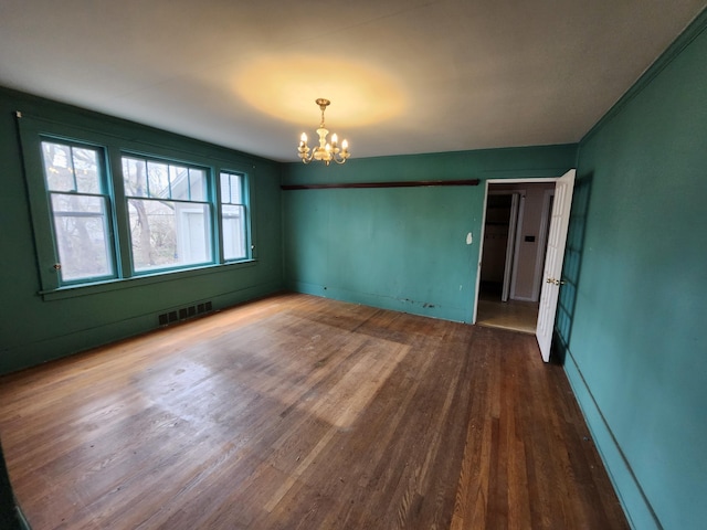 309 N Main St, Scottville, MI 49454 - empty room featuring baseboards, wood finished floors, a notable chandelier, and visible vents