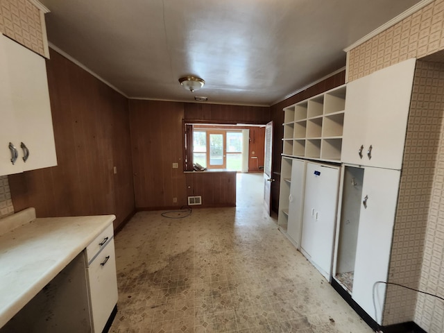 309 N Main St, Scottville, MI 49454 - kitchen with light floors, white cabinetry, visible vents, wood walls, and light countertops