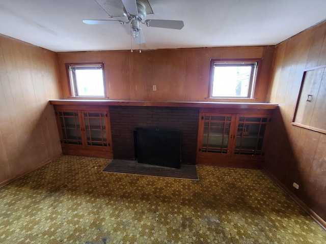 309 N Main St, Scottville, MI 49454 - unfurnished living room featuring wood walls, a ceiling fan, and a brick fireplace