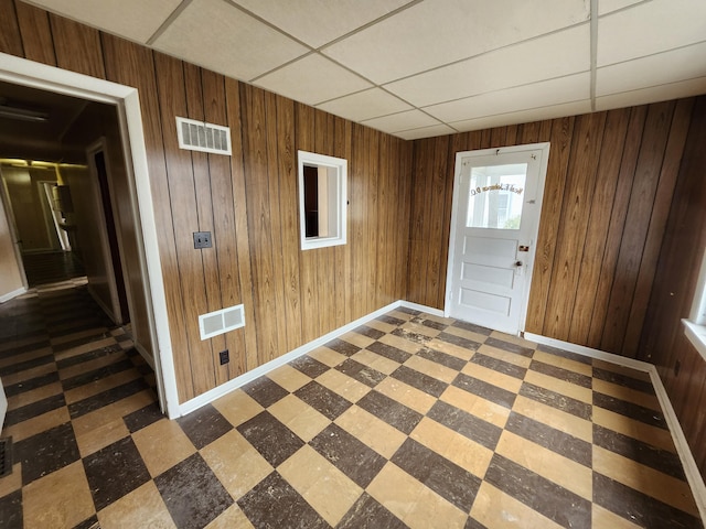 309 N Main St, Scottville, MI 49454 - foyer entrance with tile patterned floors, a paneled ceiling, wooden walls, and visible vents