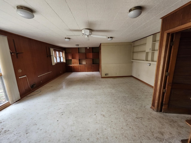 309 N Main St, Scottville, MI 49454 - unfurnished living room featuring ceiling fan, baseboards, wooden walls, and light floors