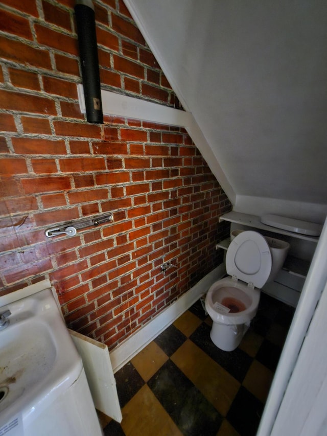 309 N Main St, Scottville, MI 49454 - bathroom with toilet, tile patterned floors, and brick wall
