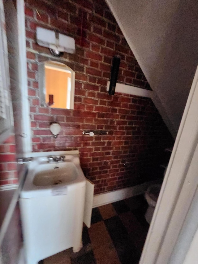 309 N Main St, Scottville, MI 49454 - bathroom featuring a sink, tile patterned floors, vaulted ceiling, and brick wall