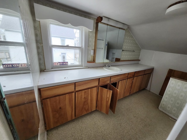 309 N Main St, Scottville, MI 49454 - kitchen featuring a sink, brown cabinetry, light countertops, and vaulted ceiling