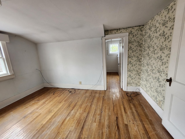 309 N Main St, Scottville, MI 49454 - unfurnished room with wallpapered walls, baseboards, lofted ceiling, and hardwood / wood-style flooring