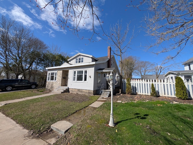 309 N Main St, Scottville, MI 49454 - bungalow-style home featuring a chimney, fence, and a front lawn