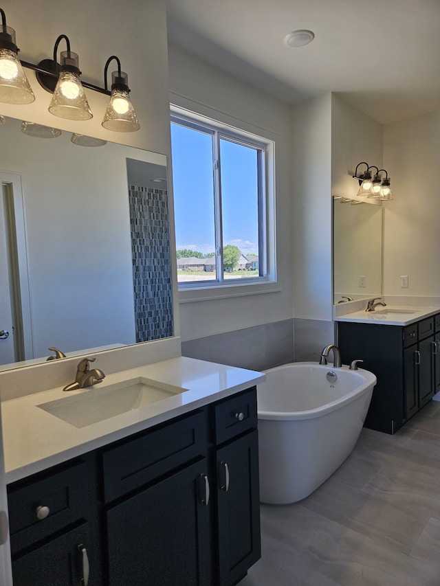 full bath with a freestanding bath, two vanities, and a sink