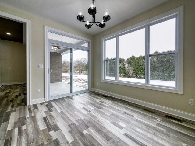 unfurnished dining area with visible vents, baseboards, a notable chandelier, and wood finished floors